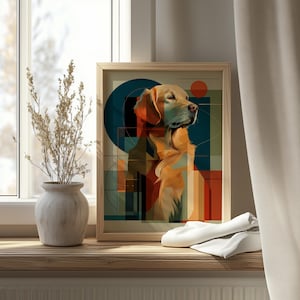 Op de afbeelding: Een ingelijste kunstprint met een golden retriever hond met een geometrische achtergrond in tinten oranje, blauwgroen en bruin. De hond kijkt naar rechts, met een serene uitdrukking. Het kunstwerk staat op een houten oppervlak bij een raam.