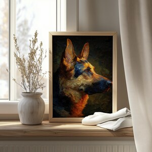 Op de afbeelding: Een ingelijst olieverfschilderij van een Duitse herdershond in profiel. Het kunstwerk toont een palet van bruin, zwart en goud, tegen een donkergroene achtergrond. De ingelijste foto staat op een houten vensterbank, met een vaas en gedroogde planten.