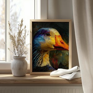 Op de afbeelding: Een ingelijst olieverfschilderij van een ganzenkop, met een levendig kleurenpalet van blauw, geel en oranje. Het kunstwerk wordt tentoongesteld op een houten vensterbank, naast een vaas met gedroogde planten en een gevouwen witte doek.