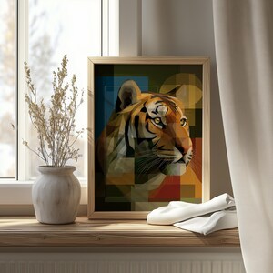Op de afbeelding: Een ingelijste kunstprint met een geometrisch tijgerportret. Het kunstwerk gebruikt een mozaïekstijl met oranje, bruine, blauwe en gele tinten. De print wordt weergegeven op een houten vensterbank.