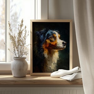 Op de afbeelding: Een ingelijst olieverfschilderij van een hond met een zwarte, witte en bruine vacht. De hond is in profiel afgebeeld, met een geconcentreerde blik. Het kunstwerk wordt tentoongesteld op een houten vensterbank, naast een vaas met gedroogde planten.