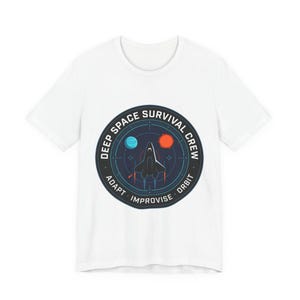 May include: White t-shirt featuring a circular graphic with the text "DEEP SPACE SURVIVAL CREW". The graphic includes a spaceship, two celestial bodies, and the words "ADAPT", "IMPROVISE", and "ORBIT".