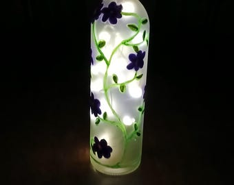 Wine bottle with acrylic flowers painted on the outside, while a cork supplies lights for the inside.
