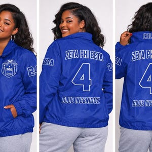 May include: A royal blue windbreaker jacket featuring white screen-printed text and graphics. The front displays a Zeta Phi Beta crest, while the back features the text Zeta Phi Beta, the number 4, and the words Blue Ingeniouz in white lettering.