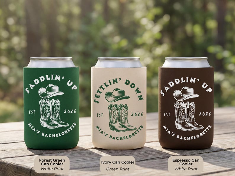 Puede incluir: Tres enfriadores de latas en verde bosque, marfil y espresso. Cada uno presenta un sombrero de vaquero y botas con el texto "Saddlin' Up" o "Settlin' Down", "Mia's Bachelorette" y el a&ntilde;o 2026.