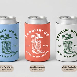 Puede incluir: Tres enfriadores de latas en azul, coral y blanco. El enfriador azul tiene un sombrero verde y un gr&aacute;fico de botas con el texto "Settlin' Down". El enfriador coral tiene un sombrero blanco y un gr&aacute;fico de botas con el texto "Saddlin' Up". El enfriador blanco tiene un sombrero verde y un gr&aacute;fico de botas con el texto "Settlin' Down".