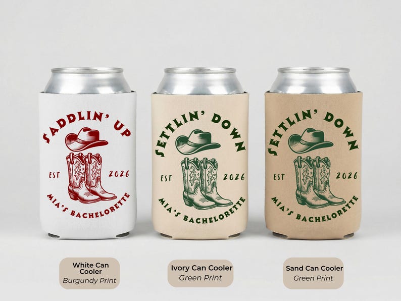 Puede incluir: Tres enfriadores de latas con dise&ntilde;os tem&aacute;ticos de vaqueros. El enfriador blanco tiene una impresi&oacute;n burdeos con un sombrero y botas de vaquero, el texto dice "Saddlin' Up". Los enfriadores marfil y arena tienen una impresi&oacute;n verde con un sombrero y botas de vaquero, el texto dice "Settlin' Down".