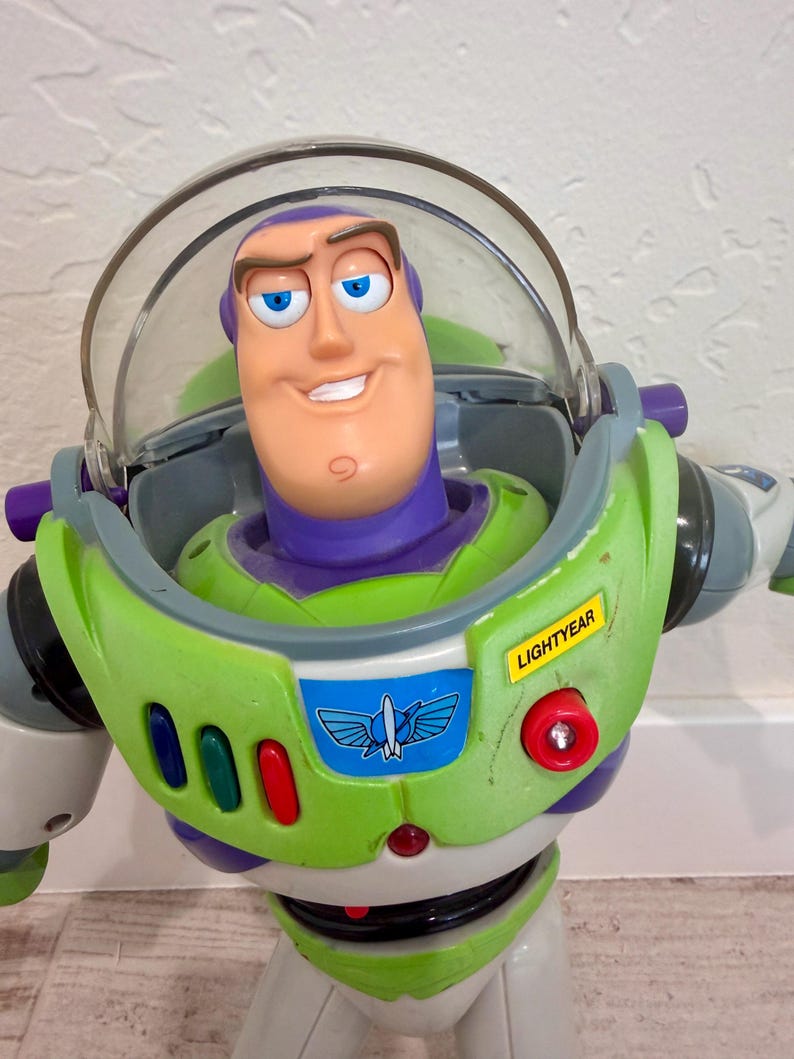 May include: A Buzz Lightyear action figure, featuring a green and white spacesuit with purple accents. The figure has a clear helmet, a smiling face, and the name "LIGHTYEAR" on the chest. The toy is a popular character from the Toy Story franchise.