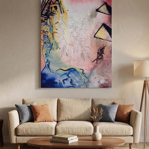 May include: Abstract art print featuring a surrealist composition with a central figure and geometric shapes. The artwork uses a palette of blues, pinks, and yellows. The print is displayed above a beige sofa with decorative pillows and a wooden coffee table.