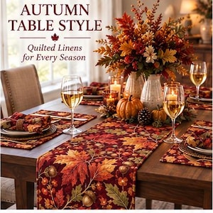 May include: A table runner and placemats featuring a quilted pattern of autumn leaves and acorns in shades of red, orange, and brown. The text reads AUTUMN TABLE STYLE and Quilted Linens for Every Season. The table is set with wine glasses and pumpkins.