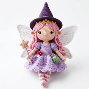May include: A crocheted doll featuring pink hair, a purple witch hat with a gold crown, and white wings. The doll wears a light purple dress with a small red mushroom and a green potion bottle attached, and holds a beige star-tipped wand.