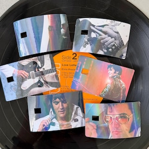 Puede incluir: Seis separadores de discos hologr&aacute;ficos con im&aacute;genes de Elvis Presley, dispuestos sobre un disco de vinilo negro. Cada separador rectangular tiene un peque&ntilde;o recorte. Las im&aacute;genes incluyen a Elvis con una guitarra, en concierto y con gafas de sol. La etiqueta del &aacute;lbum es visible.