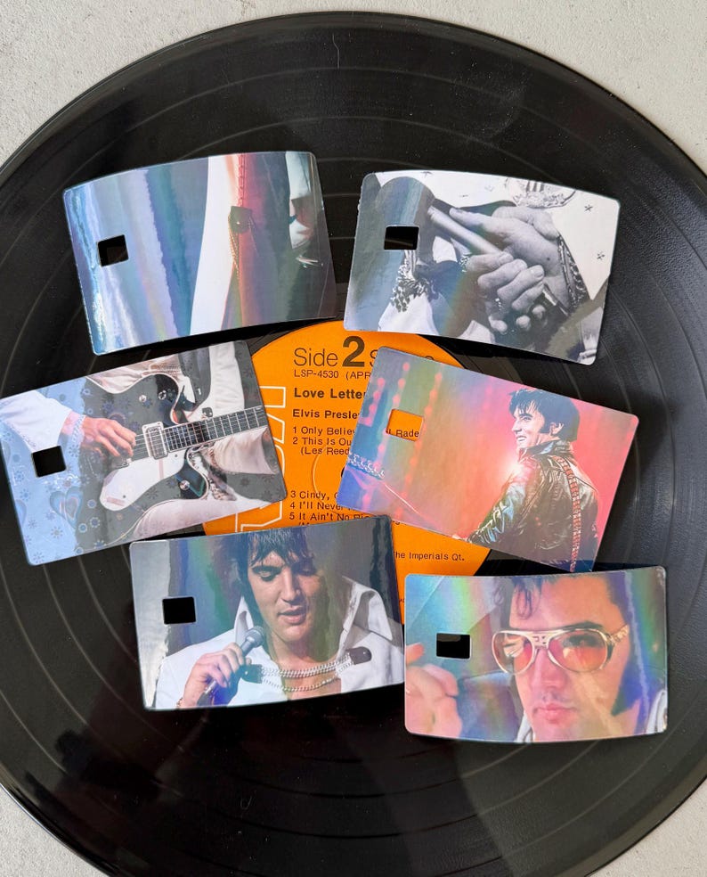 Puede incluir: Seis separadores de discos hologr&aacute;ficos con im&aacute;genes de Elvis Presley, dispuestos sobre un disco de vinilo negro. Cada separador rectangular tiene un peque&ntilde;o recorte. Las im&aacute;genes incluyen a Elvis con una guitarra, en concierto y con gafas de sol. La etiqueta del &aacute;lbum es visible.