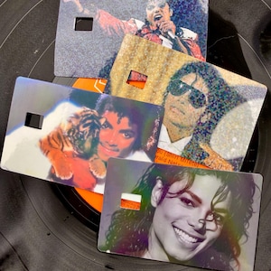 Peut inclure: Quatre cartes rectangulaires pr&eacute;sentant divers portraits photographiques de Michael Jackson. Une carte le montre en train de chanter, une autre avec des lunettes de soleil, une tenant un b&eacute;b&eacute; tigre et une souriante. Chaque carte a une d&eacute;coupe carr&eacute;e.