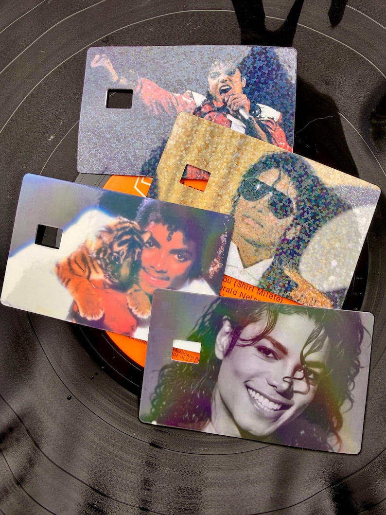 Peut inclure: Quatre cartes rectangulaires pr&eacute;sentant divers portraits photographiques de Michael Jackson. Une carte le montre en train de chanter, une autre avec des lunettes de soleil, une tenant un b&eacute;b&eacute; tigre et une souriante. Chaque carte a une d&eacute;coupe carr&eacute;e.