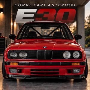Puede incluir: Un coche BMW E30 de color rojo brillante visto desde el frente, con una parrilla negra, faros redondos e intermitentes ámbar. El texto COPRI FARI ANTERIORI E30 aparece en blanco y rojo en la parte superior, con una jaula antivuelco visible.