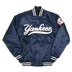May include: A navy blue satin bomber jacket featuring the word Yankees in white script across the chest. The jacket has a snap-button front closure, striped ribbed collar, cuffs, and hem, and a circular team logo patch on the upper left sleeve.