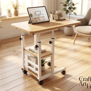 May include: A mobile side table with a light wood-grain top and two lower shelves, supported by a white metal frame with adjustable height knobs. The unit features four black caster wheels, a tablet stand, and a desk organizer on the surface.
