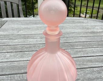 Botella decorativa de tocador acanalada de satén rosa con tapa.