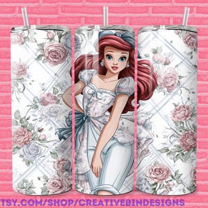 May include: A 20oz stainless steel tumbler featuring a floral design with pink and blue roses, a diamond pattern, and a cartoon illustration of a princess. The tumbler has a straw and a lid. The text "PNG" is visible.