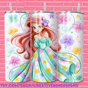 May include: Three cylindrical tumblers with straws featuring a cartoon character with long red hair and a teal off-the-shoulder dress. The design includes a white background with scattered watercolor-style flowers in pink, yellow, purple, and teal.