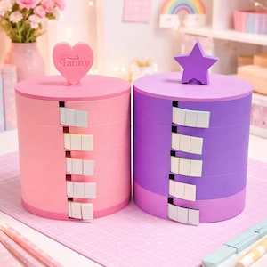 May include: Two pastel-colored, round storage containers. One is pink with a heart-shaped topper that reads "Creative Fanny", the other is purple with a star-shaped topper. Each has multiple pull-out drawers.