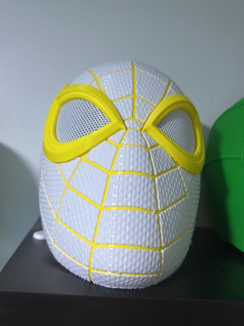 Puede incluir: Una m&aacute;scara de Spider-Man blanca y amarilla. La m&aacute;scara presenta una superficie texturizada con l&iacute;neas de telara&ntilde;a amarillas y contornos de ojos amarillos. Las aberturas para los ojos son de material de malla. Es un art&iacute;culo de cosplay o disfraz.