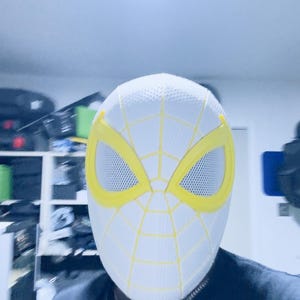 Puede incluir: M&aacute;scara blanca de Spider-Man con detalles amarillos. La m&aacute;scara presenta contornos de ojos amarillos y un dise&ntilde;o de telara&ntilde;a amarilla sobre la superficie blanca. Las aberturas de los ojos son de malla. Accesorio de disfraz.