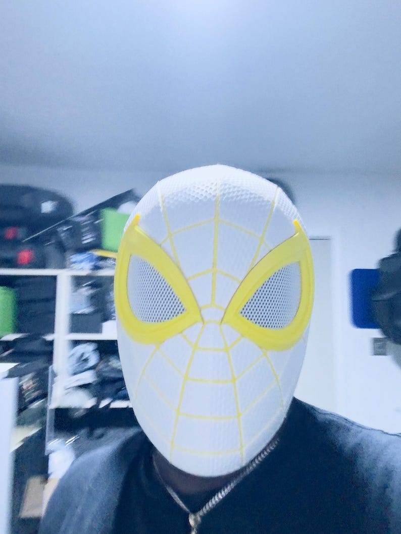 Puede incluir: M&aacute;scara blanca de Spider-Man con detalles amarillos. La m&aacute;scara presenta contornos de ojos amarillos y un dise&ntilde;o de telara&ntilde;a amarilla sobre la superficie blanca. Las aberturas de los ojos son de malla. Accesorio de disfraz.