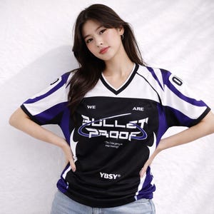 Peut inclure: Un maillot de corps noir, blanc et violet à col en V avec le texte "BULLET PROOF" et "WE ARE" imprimé sur le devant. Le maillot a des manches blanches avec des accents violets et le numéro "0" sur la manche droite.