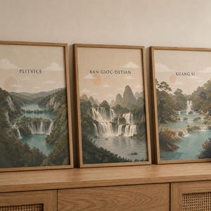 May include: Three framed vertical art prints featuring landscape illustrations of waterfalls. The prints are labelled Plitvice, Ban Gioc-Detian, and Kuang Si. Each image depicts a tiered waterfall with blue water, green trees, and a pale sky.
