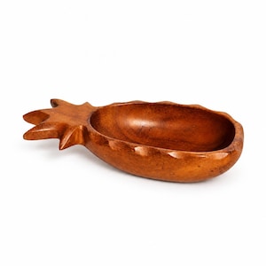 May include: A carved wooden bowl shaped like a pineapple with a smooth, polished finish. The bowl features a deep, rounded basin and a textured, pointed leaf design at one end, showcasing the natural brown wood grain and warm colour tones.
