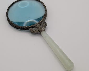Lupa antigua de estilo victoriano con mango de jade y lente azul en tono plateado ornamentada para escritorio.
