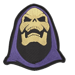 May include: An embroidered patch featuring a stylised skull face in light yellow with deep black eye sockets and a wide open mouth. The skull is framed by a purple hood against a black background, all enclosed within a thick black stitched border.