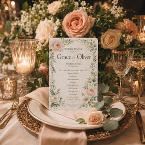 May include: A wedding program with the names "Grace & Oliver" and the date "November 14, 2026" is displayed on a table setting. The program is decorated with floral elements and sits on a plate with a gold rim, surrounded by flowers and candles.