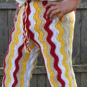 May include: Crocheted pants with a wavy pattern in red, white, yellow, and beige.
