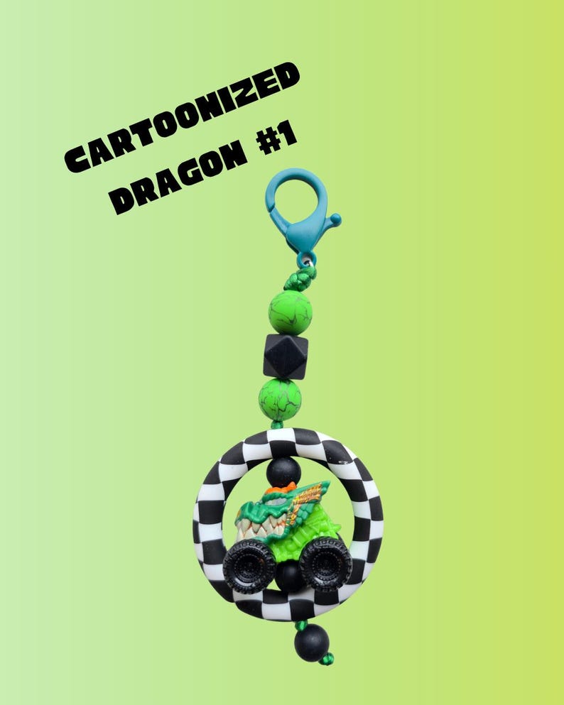 K&ouml;nnte beinhalten: Ein Cartoon-Drachen-Schl&uuml;sselanh&auml;nger in Gr&uuml;n und Schwarz. Der Drache befindet sich in einem schwarz-wei&szlig; karierten Kreis. Der Schl&uuml;sselanh&auml;nger hat einen blauen Verschluss und ist mit gr&uuml;nen und schwarzen Perlen verziert. Der Text auf dem Bild lautet "Cartoonized Dragon #1".