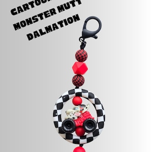 K&ouml;nnte beinhalten: Ein Schl&uuml;sselanh&auml;nger mit einem Cartoon-Dalmatiner, der einen roten Monstertruck in einem schwarz-wei&szlig; karierten Ring f&auml;hrt. Der Schl&uuml;sselanh&auml;nger hat rote und schwarze Perlen und den Text "Cartoonized Monster Mutt Dalmatian".