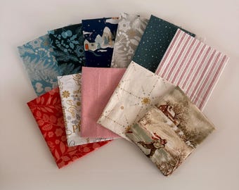 Può includere: Una collezione di quadrati di tessuto piegati con vari motivi a tema festivo, tra cui strisce rosse e bianche, un paesaggio invernale con una persona che pattina sul ghiaccio, stampe floreali blu e bianche e tessuto blu scuro.