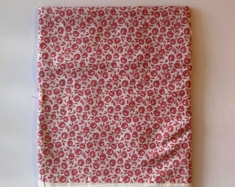 Può includere: Un pezzo di tessuto rettangolare caratterizzato da un motivo denso e ripetitivo di piccoli fiori rosa scuro e foglie verdi su sfondo bianco. Il tessuto presenta un orlo dritto e pulito lungo il bordo inferiore, che mette in risalto la stampa floreale.