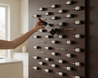 May include: A dark wood wine rack mounted on a wall, holding numerous wine bottles. A hand is reaching for a bottle. The rack has gold-colored metal holders. The bottles are arranged in rows.