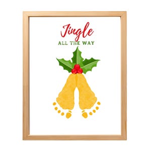 May include: A framed print featuring the text Jingle ALL THE WAY in red and green. Below the text is a graphic of green holly leaves with three red berries, positioned above two yellow footprints arranged to resemble a pair of bells.