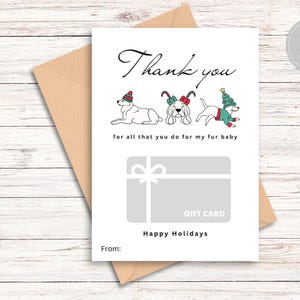 Puede incluir: Una tarjeta de felicitación blanca de 5x7 pulgadas con un sobre color canela. La tarjeta incluye el texto Thank you for all that you do for my fur baby, ilustraciones de tres perros con ropa festiva, un gráfico de tarjeta de regalo gris y el texto Happy Holidays y From.