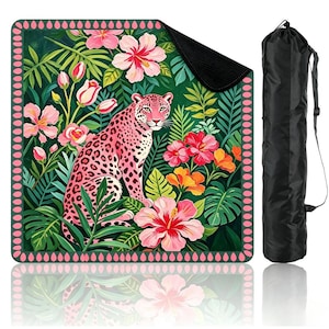 May include: A square mat featuring a pink leopard surrounded by tropical green foliage and vibrant pink, orange, and red hibiscus flowers, framed by a pink teardrop border, accompanied by a black cylindrical carrying bag with a shoulder strap.