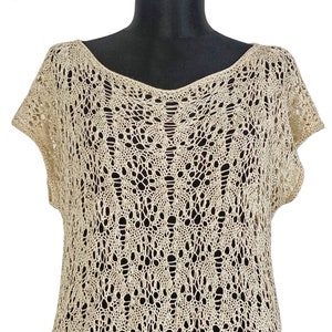 May include: A beige crochet top with a delicate openwork pattern. The top has a v-neck and short sleeves.