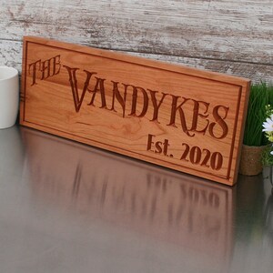 May include: A wooden sign with the text "The Vandykes Est. 2020" carved into it.