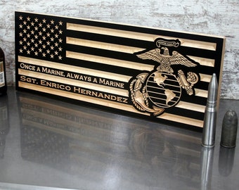 May include: A wooden American flag with black stripes and stars, engraved with the Marine Corps emblem and the text "Once a Marine, Always a Marine" and "Sgt. Enrico Hernandez". Two bullets are next to the flag.