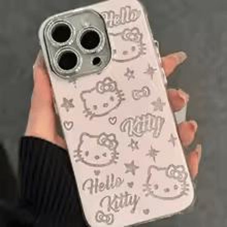 Puede incluir: Una funda de tel&eacute;fono rosa claro con un anillo de c&aacute;mara plateado. La funda presenta m&uacute;ltiples ilustraciones del personaje Hello Kitty, estrellas y las palabras "Hello Kitty" en una fuente l&uacute;dica.