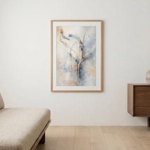 May include: An abstract art print in a wooden frame hangs on a white wall. The artwork features soft blue, beige, and white colors. A beige sofa and a wooden cabinet with a vase and dried plant are also in the room.