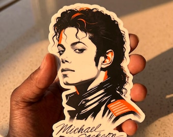 May include: A sticker featuring a stylized illustration of Michael Jackson. The image is in black, white, and orange, with the singer's name in a cursive font. The sticker has a white border and a glossy finish.
